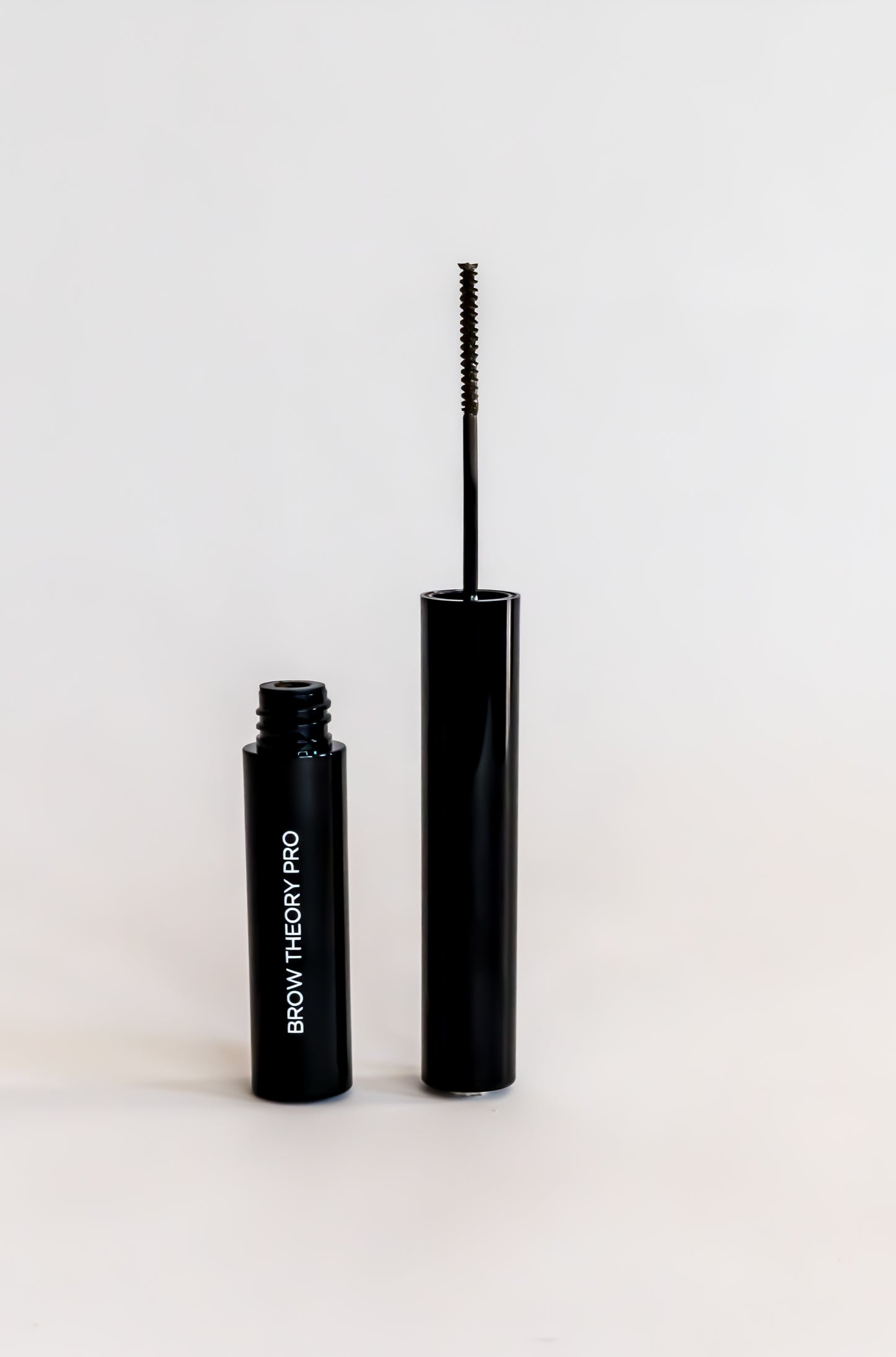 black tube with small spoolie brush to apply tinted eyebrow gel in shade deep brunette